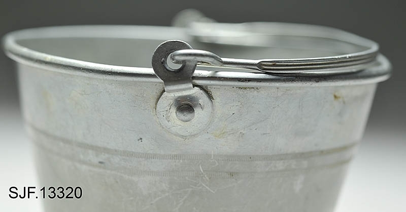Bærspann i aluminium. Spannet har en fot som er noe breiere enn spannets bunn, og det er preget inn 4 striper langs spannets utside. Det er festet en bærehank til spannet. 

Spannet er brukt av giver da hun var ei lita jente, og av hennes mor som var født ca. 1910. Spannet ble brukt på bærtur. Giver forteller at det til sammen har blitt båret mange hundre kilo blåbær i dette lille spannet. Plukkested var først i Heradsbygda, og deretter Jømna. 