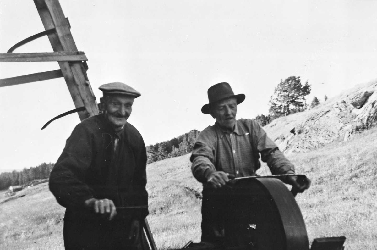To eldre karer kvesser ljå på slipstein. Iver Furuhovde (1880-1966), Ola Hansen Sæther (1879-)fra Oppdal.