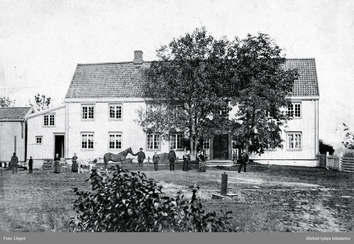 Ukjent gårdsbruk, våningshus og stabbur med familien og hest og ku oppstilt foran huset.
Oluf Wilhelm Falck-Ytter (1832-1914), byfogd i Sarpsborg, var givers oldefar og tidligere eier av fotografiet. Ettersom han var byfogd i Sarpsborg kan vi kanskje anta at motivet er fra Sarpsborgs omegn i Østfold, eller kanskje et annet sted i Norge, kanskje en sorenskrivergård eller en annen storgård f.eks. ved Mjøsbygdene - Akershus/Hedmark/Oppland?
