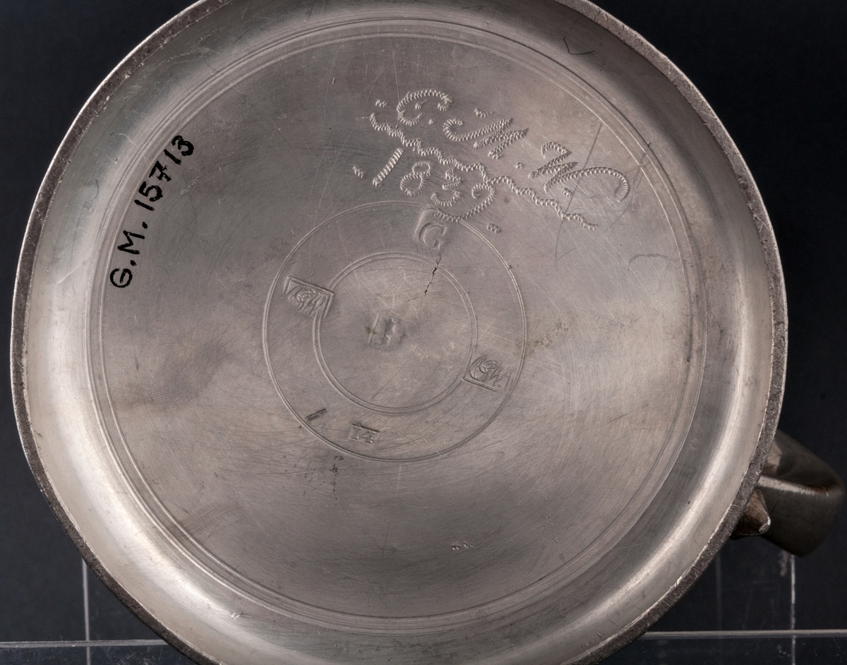 Tennstop, tillverkat 1839 av Carl Gustaf Wigholm, Gävle.
Raka sidor, på locket medaljong, med porträtt av Karl XIV Johan. I botten inristat C.M.W. 1839.