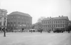 Vy över Stora torget i Linköping en tidig vårdag 1926. Byggnaden under uppförande är det så kallade Affärspalatset som efter färdigställande bl.a. skulle komma att inrymma Sydsvenska banken, Café Continental och Ateljé Röding. Bussen till höger gick i trafik mellan stadsdelarna Tannefors och Gottfridsberg.