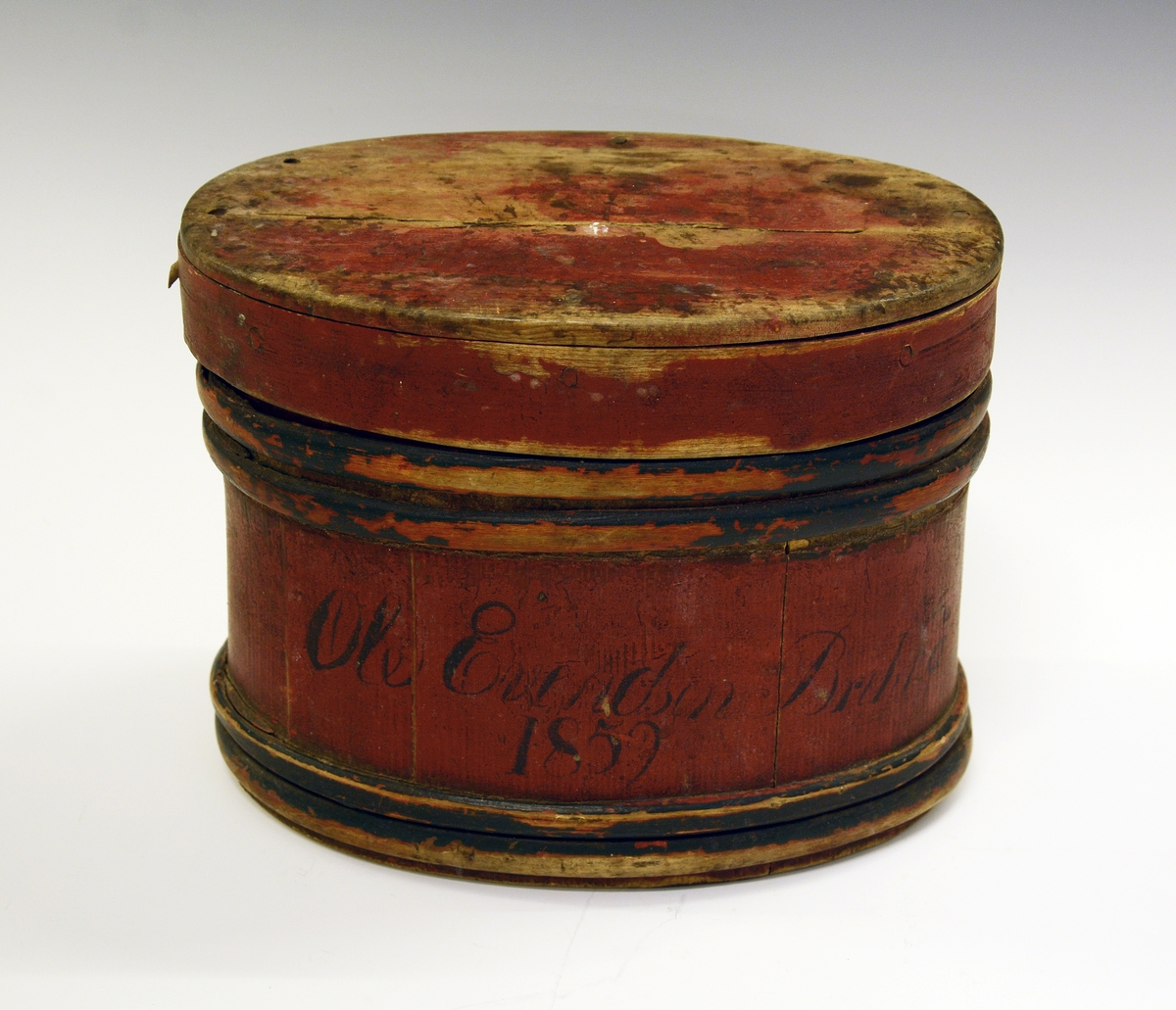 Eske (ask) med lokk. Lagget. Brunmalt med blå gjorder. Påskrevet "Ole Evendsen Brekka 1859". I bunnen er innskåret "1823" og "O".