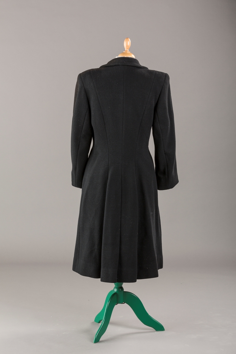 Innsvinget liv, pynteklaffer ved brystet foran. 
Stikklommer foran.
Skulderputer
Fire trukne knapper
Avrundet krage