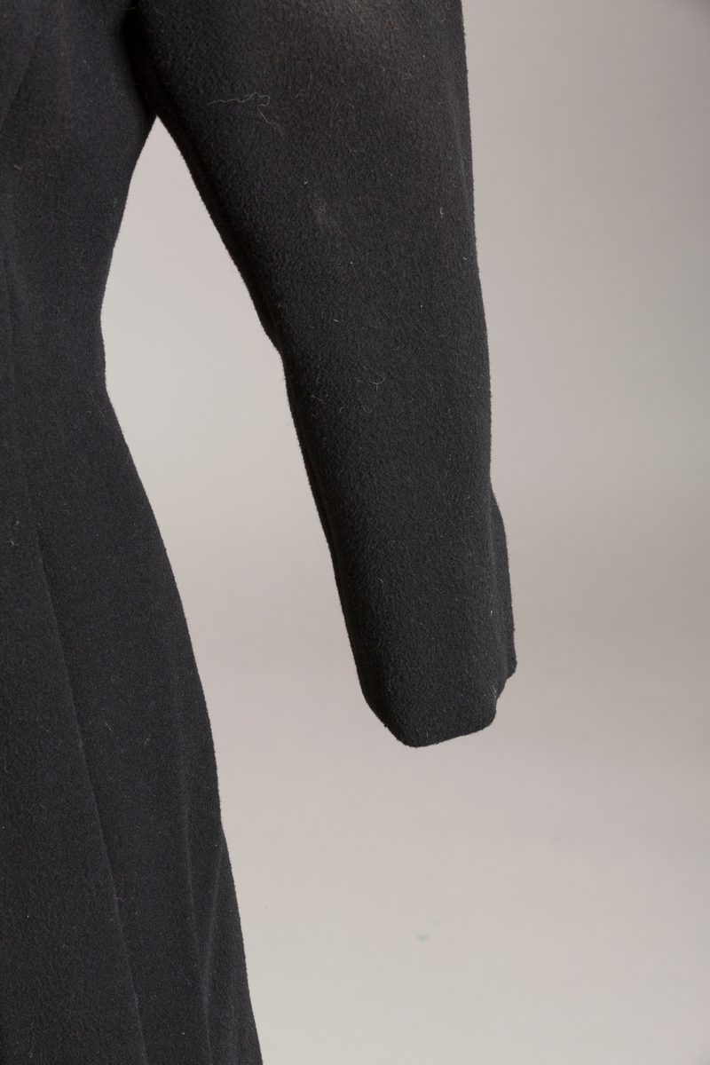 Innsvinget liv, pynteklaffer ved brystet foran. 
Stikklommer foran.
Skulderputer
Fire trukne knapper
Avrundet krage