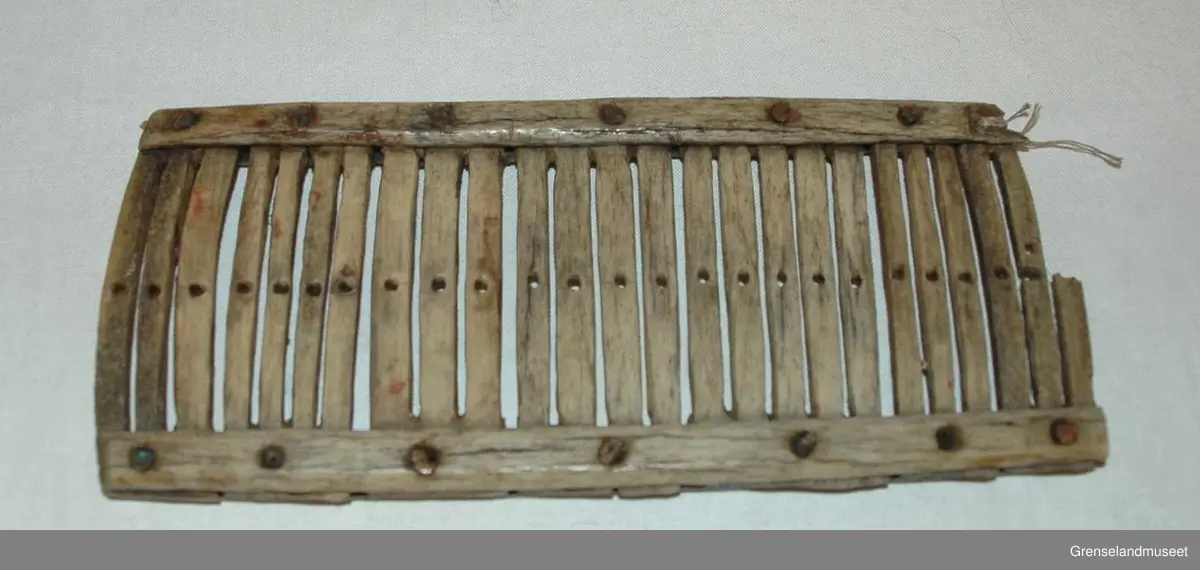 Sammensatt av 3-5 spiler i hver del. Ett hull i de fleste spilene. Den nest ytterste spilen på den ene siden har to hull, og den ytterste på samme side er brukket av.. Tilsammen 25 spiler. Delene er festet sammen med metallnagler.
Ingen dekor.