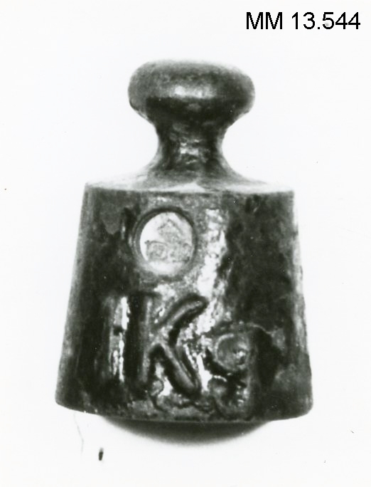 Vikt om 1 kg av järn. Märkt "1 Kg", "17  42" samt med kunglig krona. Svartmålad.