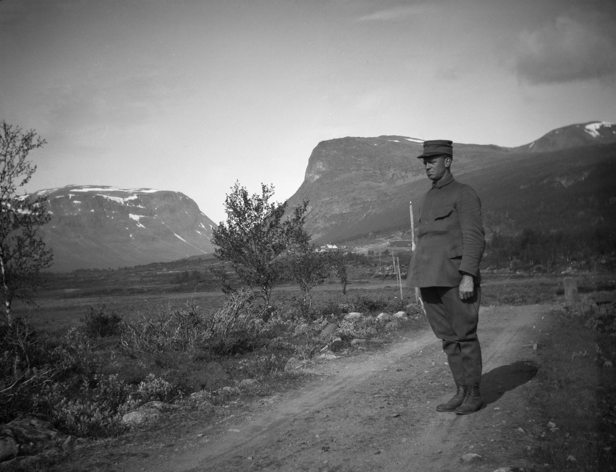 Mann i militæruniforn står på grusveg i Sikkilsdalen.