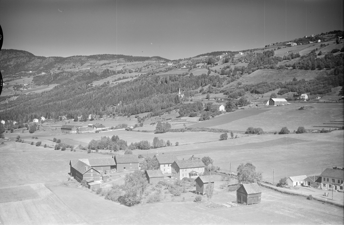 Jevne i Øyer, butikk nede til høyre i bildet, kirke midt i bildet, jordbruk, slåttonn, hesjing, blandingsskog