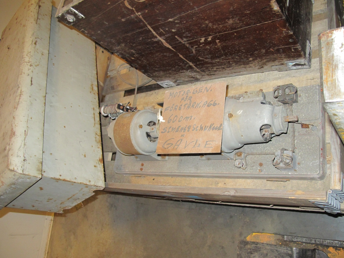 Motorgenerator för förstärkningsaggregat. 
Rektangulär huv med ventilspringa onder lockets kant. Bottenplatta med två cylindriska motorer.