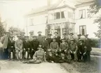 Grupporträtt av landstormens 3:e kompaniet bataljon Almström, landstormsbefäl poserar utanför hus vid Löttinge 1914.