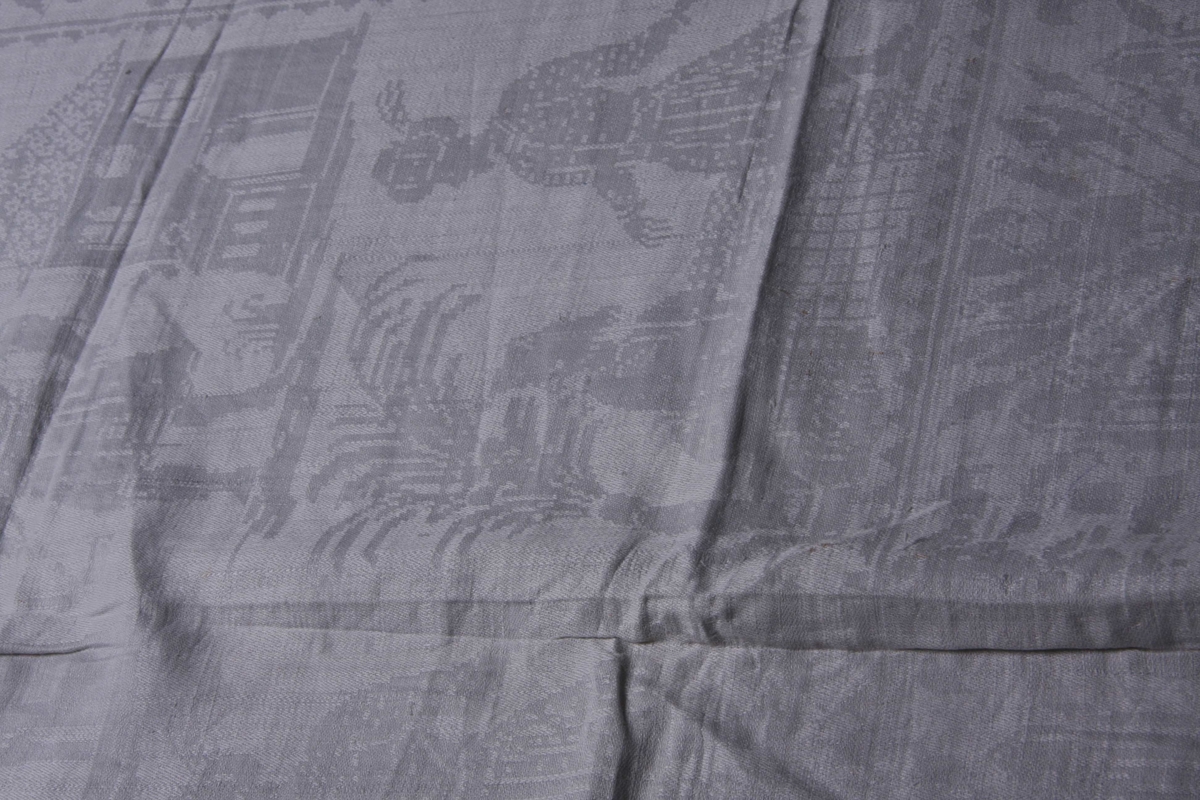 Hvit lindamask med sjakkbrett-bord langs alle fire sider. Og bred bord innenfor med trofèoppstillinger. I hvert hjørne en figur med allongeparykk. På midtpartiet en sittende og en ståendefigur ved siden, og øverst stående figur med stor hatt og tregruppe. Mønster fra beg. av 1700. Serviettene har smal fall på kortsidene.