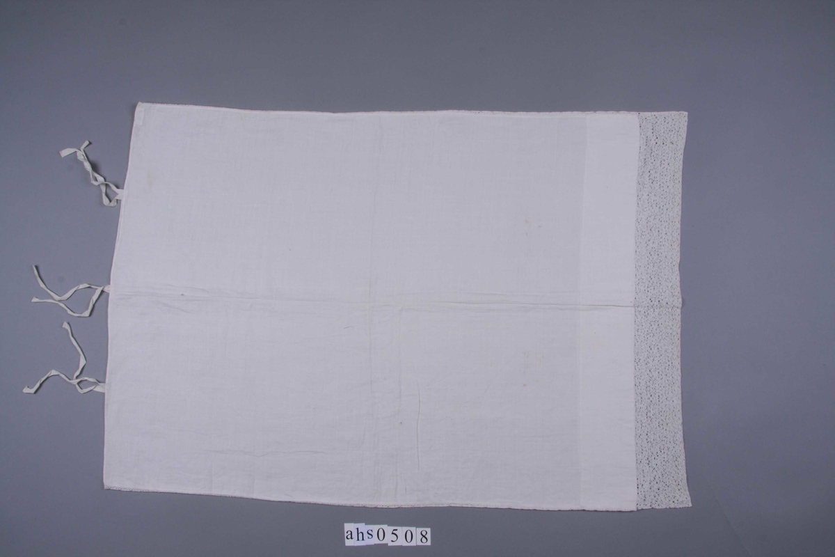 Hvit linlerret. Åpen i den ene kortsiden med smal fall og knytebånd. Den annen er sydd sammen med en 14 bred knipling, meget fin og tett i mønsteret består av to 7 cm. brede kniplinger som er sydd sammen. Meget bred fall på begge sider av kniplingen. Langsidene er sydd sammen med en 1 cm. bred knipling.