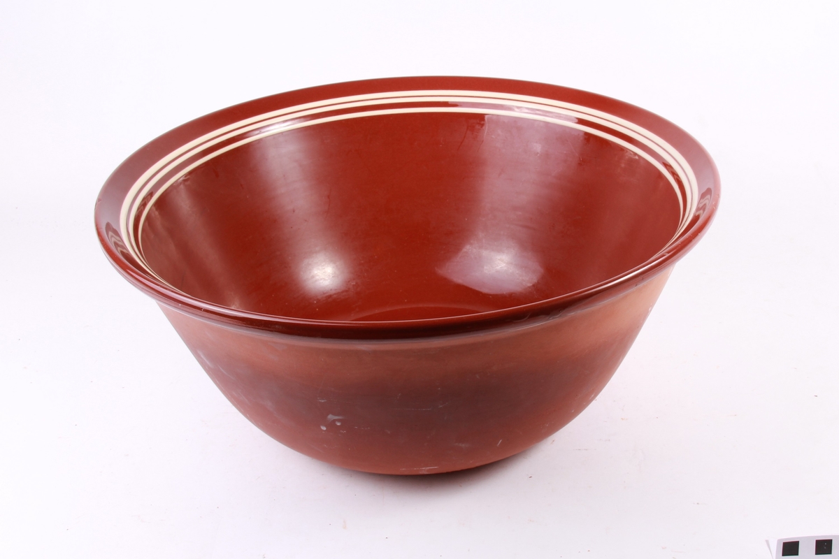 Brun glasur og tre kvite striper rundt kanten.