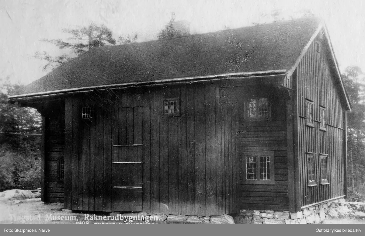 Trøgstad Bygdemuseum. Raknerudbygningen. Eksteriør. Postkort. 
Raknerudbygningen er en stuebygning med svalgang fra 1777.
Trøgstad Bygdemuseum er et av de første bygdemuseer i landet. Museet ble innviet på Olsokdagen 29. juli 1928,