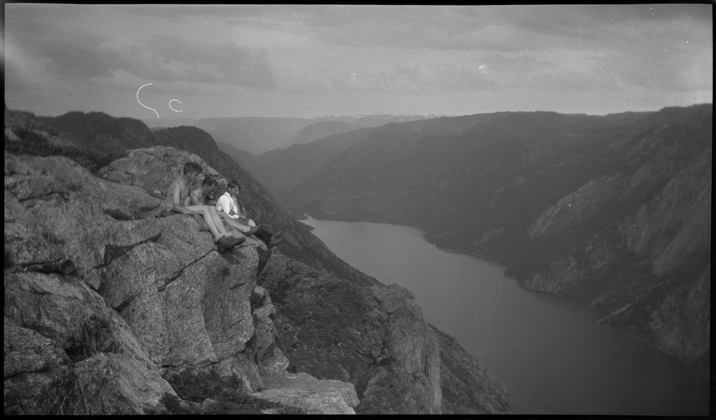 To gutter og en ung mann sitter på fjellet Svoå og titter ned i Tysdalsvatnet. Lindtner sitter i midten.