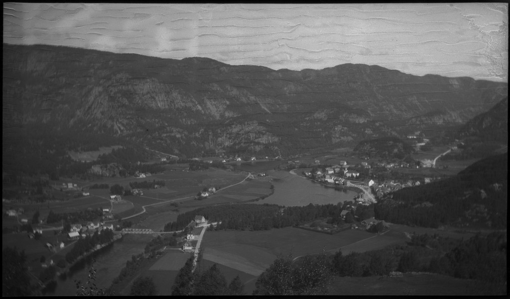 Biltur til Kvinesdal. Det er bilder tatt fra bilen fremover på veien og utover landskapet. Det er også bilder fra et tettsted ved en fjord. På bilde nr. 8 står det et hus med påskriften "HANSEN" på den andre siden av ei bru. På bilde nr. 17 sitter antageligvis Harald Bergsaker og Arne Johannessen på en stein i ei stri elv. Det er også flere bilder av en gruppe mennesker med en åpen buss. På bilde nr. 14 er L. A. B. Ådnesen til venstre.