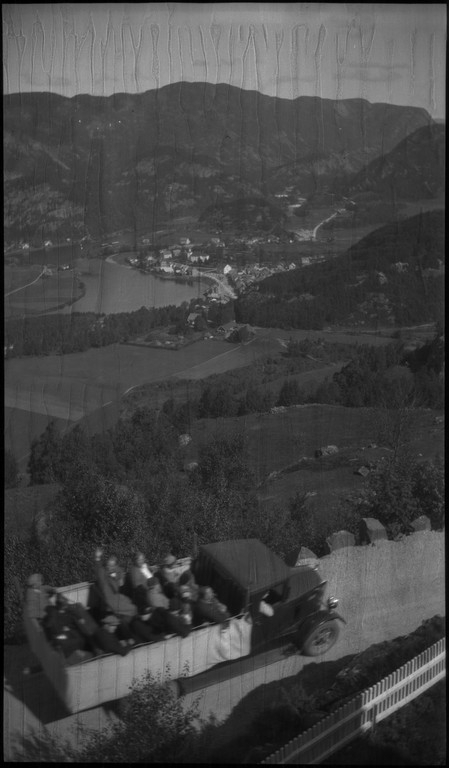 Biltur til Kvinesdal. Det er bilder tatt fra bilen fremover på veien og utover landskapet. Det er også bilder fra et tettsted ved en fjord. På bilde nr. 8 står det et hus med påskriften "HANSEN" på den andre siden av ei bru. På bilde nr. 17 sitter antageligvis Harald Bergsaker og Arne Johannessen på en stein i ei stri elv. Det er også flere bilder av en gruppe mennesker med en åpen buss. På bilde nr. 14 er L. A. B. Ådnesen til venstre.