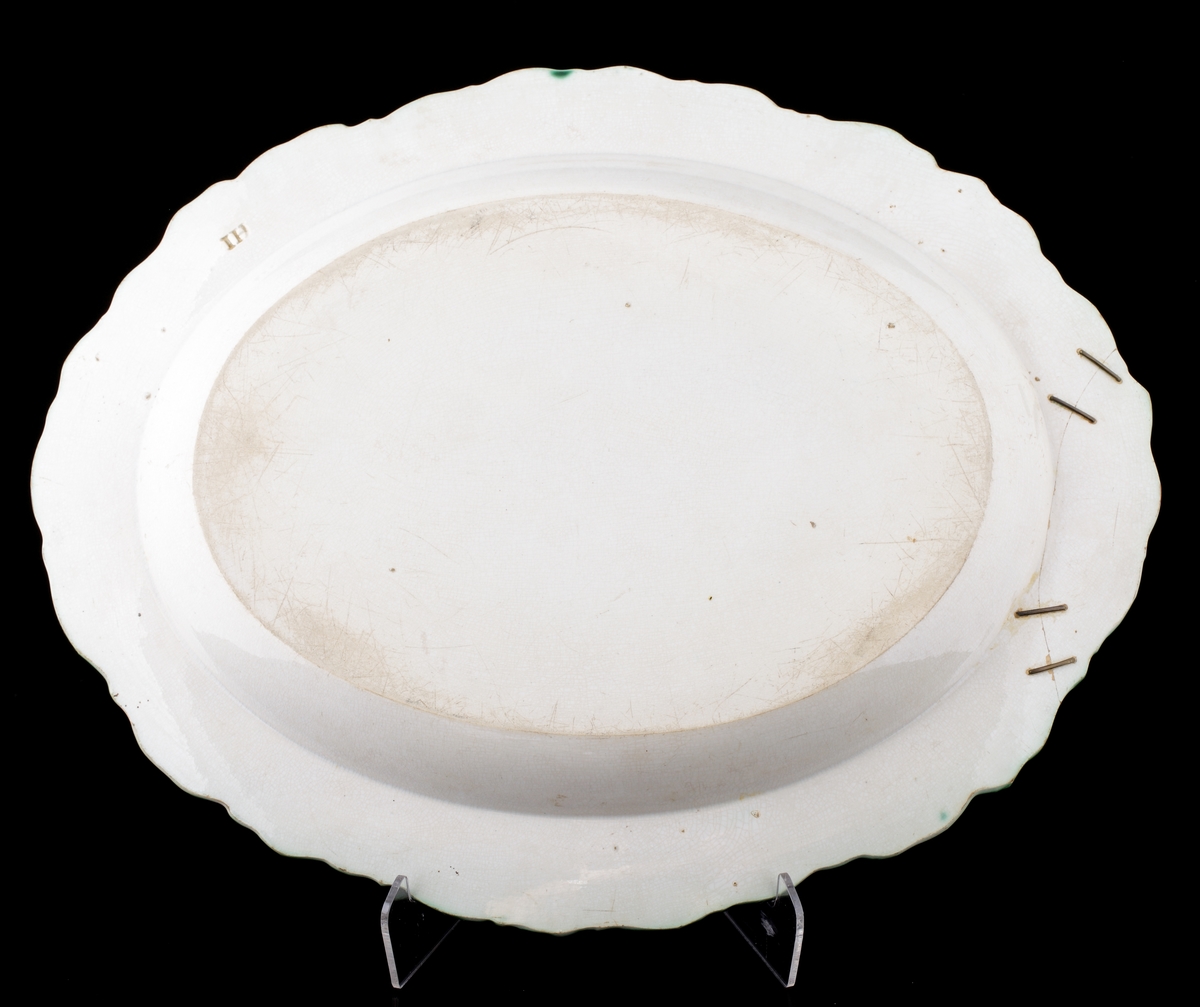 Stekfat av flintgods.
Oval modell. Vitglaserat med grön s.k. "feather edge"-kant. På fatets spegel monogram i vinrött: "JS". 
På fatet fäst en lapp med text: "Johan Sergel (1740-1814), adlad professor vid Konstakademin, Johan Sergel 1800-10, Inköp".