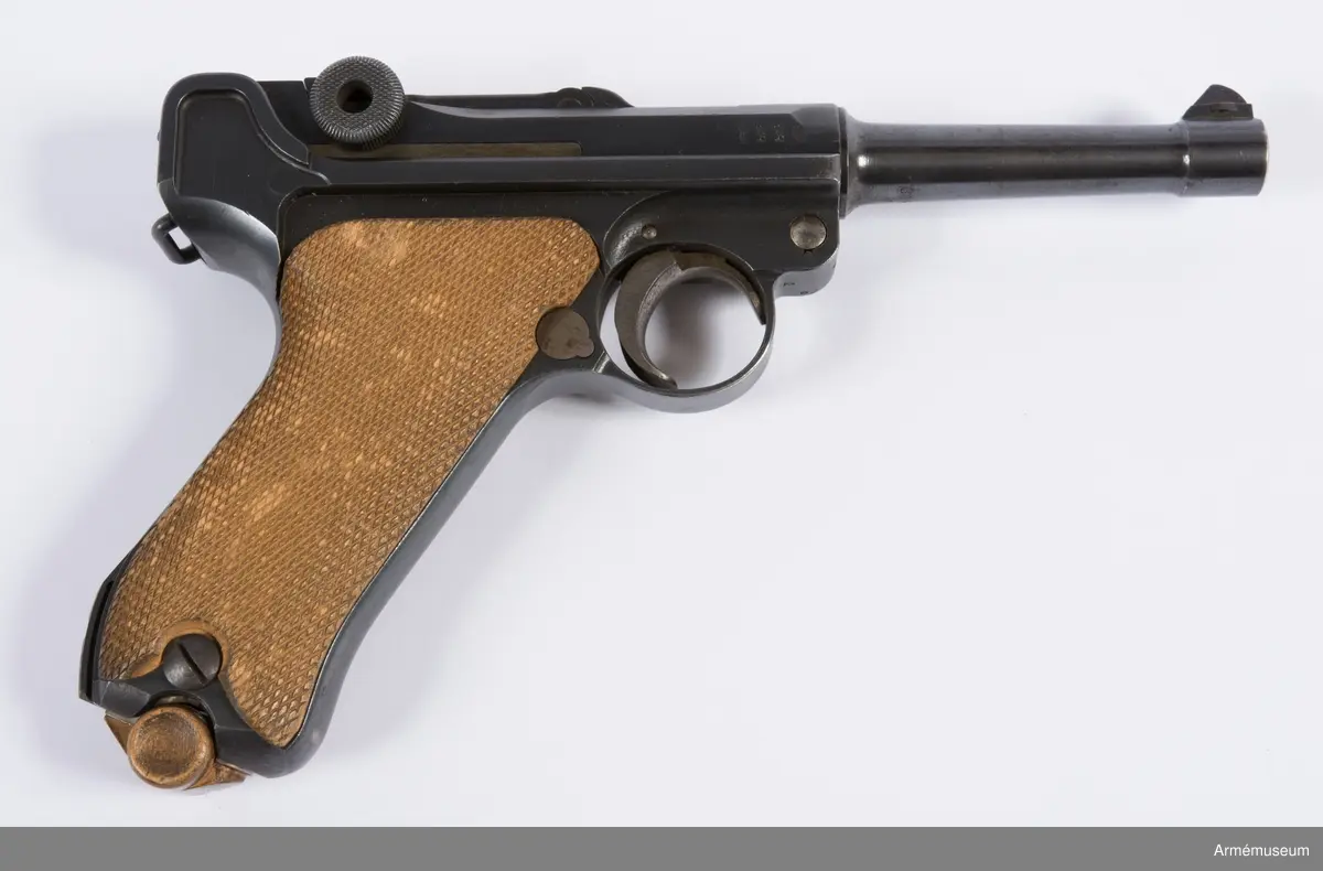 Kolvsidor av trä.
Hölster och extramagasin saknas.
Stämpel på ovansida från Deutsche Waffen- und Munitionsfabriken (DWM), Berlin. Där tillverkades de allra flesta av Parabellumpistolerna mellan 1900-1930.
