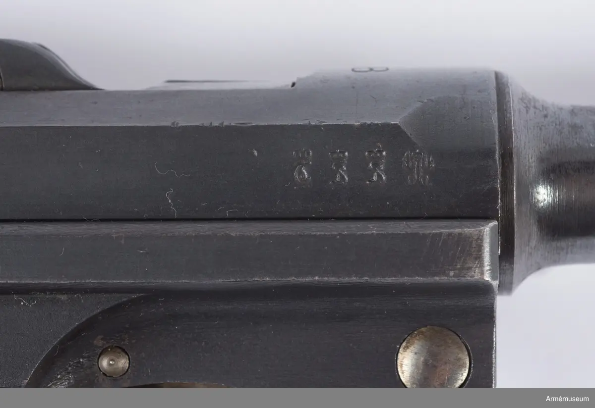 Kolvsidor av trä.
Hölster och extramagasin saknas.
Stämpel på ovansida från Deutsche Waffen- und Munitionsfabriken (DWM), Berlin. Där tillverkades de allra flesta av Parabellumpistolerna mellan 1900-1930.