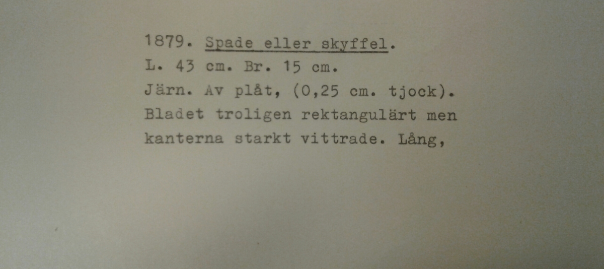 Spade eller skyffel av järnplåt. Möjligen ursprungligen rektangulär, men kanterna är starkt vittrade. Vid basen vinklas bladet i en distinkt böj upp mot en lång, svagt konisk holk för skaftet. I holken finns ett spikhål.