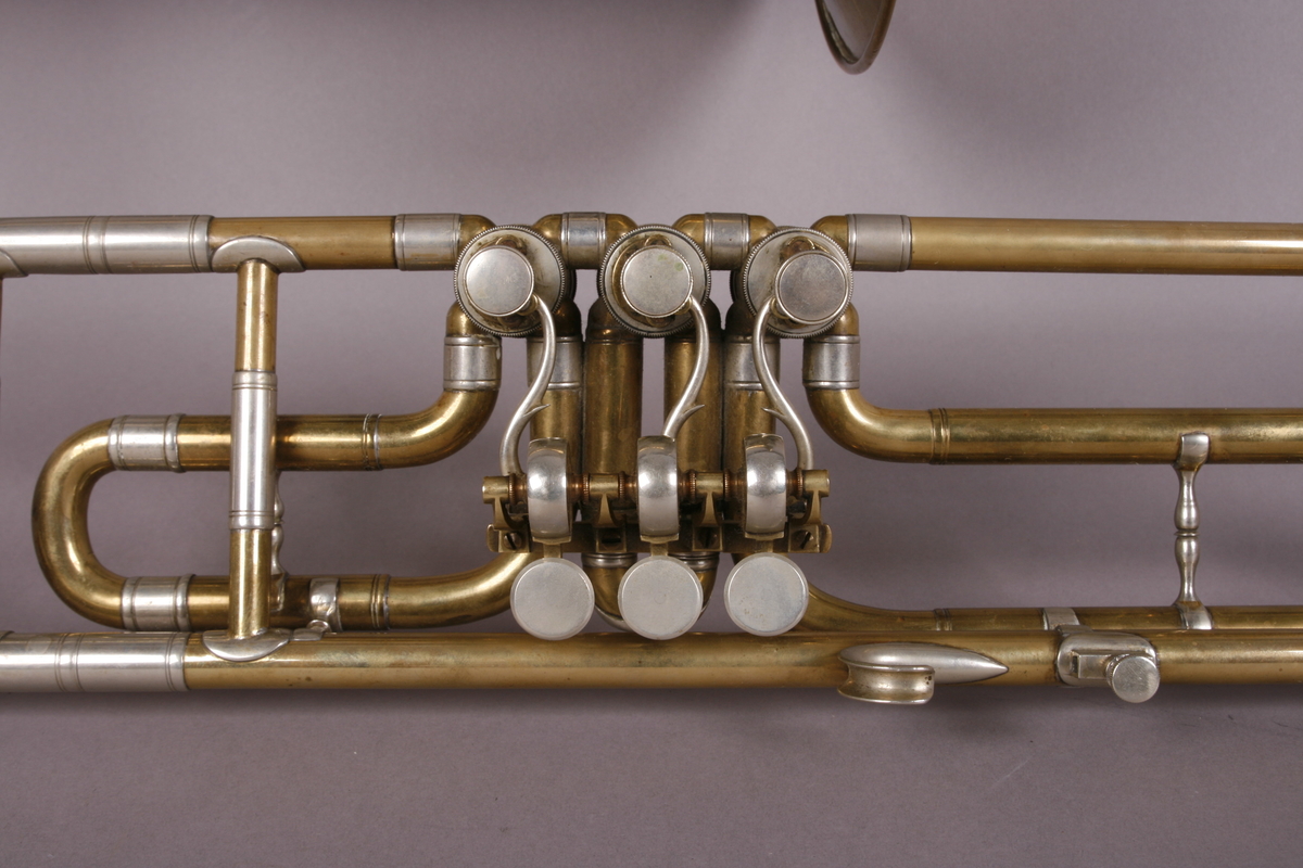 Ventilbasun, eller trombone, i messing, med dreieventiler. Tilhørende munnstykke.
