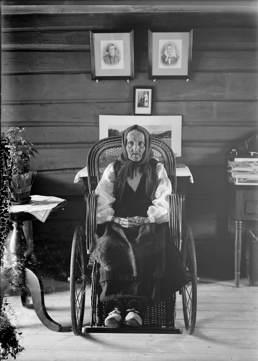 Eldre kvinne fra Otta i damaskstakk sittende i rullestol. Gunnar Kleivmellom's mor