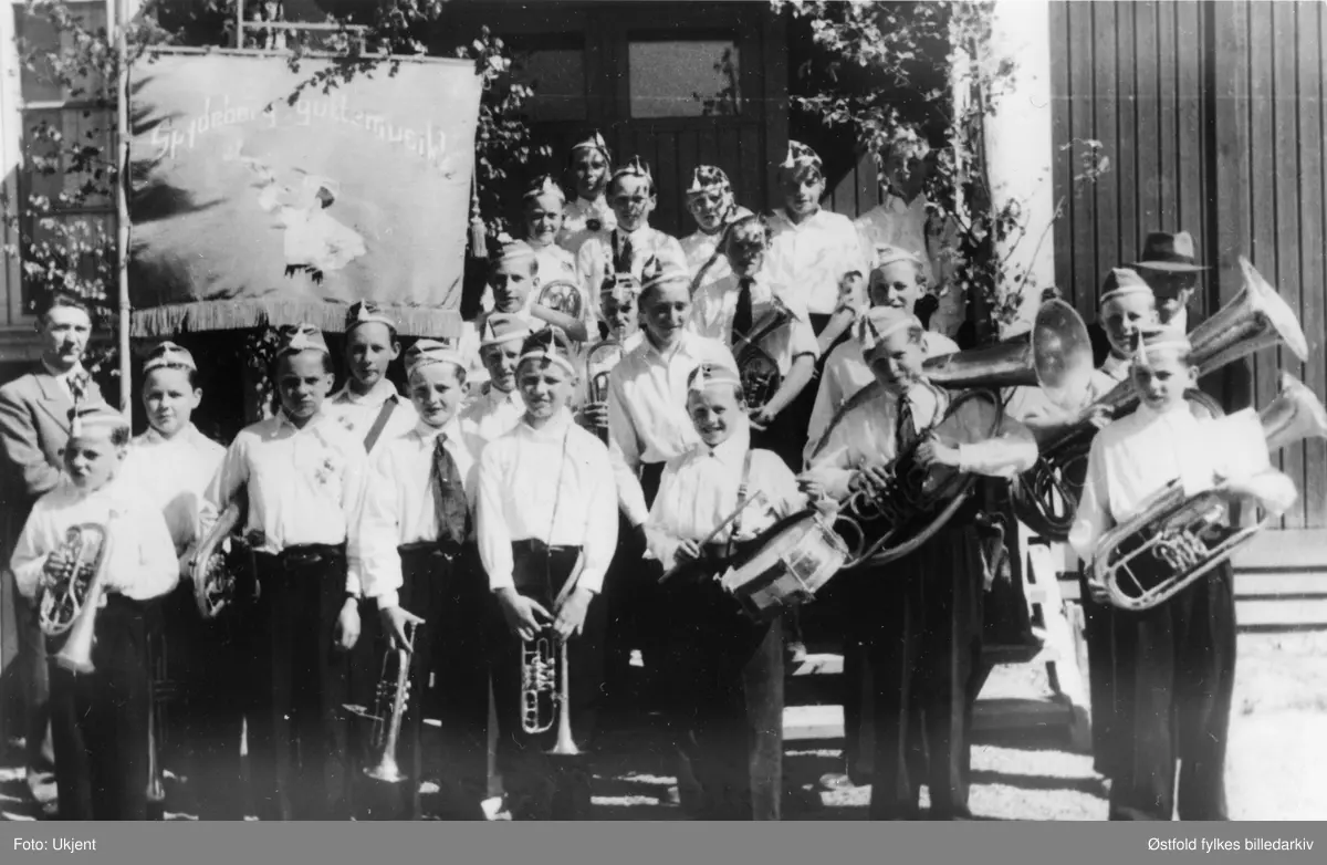 Spydeberg Guttemusikkorps i Spydeberg i 1946 (1948?).

Ved fanen formann Odd Svarstad
Foran til venstre: 
Øivind Fjeld
Ragnar Fjeld
Sigmund Grini
Emil Haugland
Øistein Kristiansen
Magne Solberg
Sigurd Syvertsen

2. rekke fra venstre: 
Knut Sølvberg
Per Svarstad 
Per Ødegård
Bjarne Gulberg
Helge Vestby
Hans Thoresen (dirigent)

3. rekke: Johan Schussler, Jon Burås, Prestby.

4. rekke: Eivind Lageraaen, Arve Holmerud, Cato Haugland, Tor Fjeld, Ivar Hagen.
Gutten helt bakerst er Finn Ødeli.