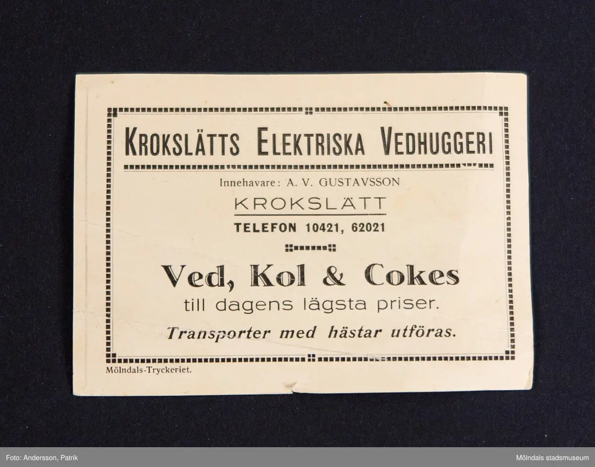Självhäftande etikett från Krokslätts elektriska vedhuggeri, tryckt av Mölndals-Tryckeriet troligtvis innan 1950-talet.

På etiketten finns texten:
"KROKSLÄTTS ELEKTRISKA VEDHUGGERI
Innehavare: A. V. GUSTAVSSON
KROKSLÄTT
TELEFON 10421, 62021

Ved, Kol & Cokes
till dagens lägsta priser.
Transporter med hästar utföras.

Mölndals-Tryckeriet."

På baksidan av etiketten finns handskriven text:
"08195

King Georg
Av Stabens Växlskyddanstalt
insynad och godkänd

Carl Svensson Boberg"
