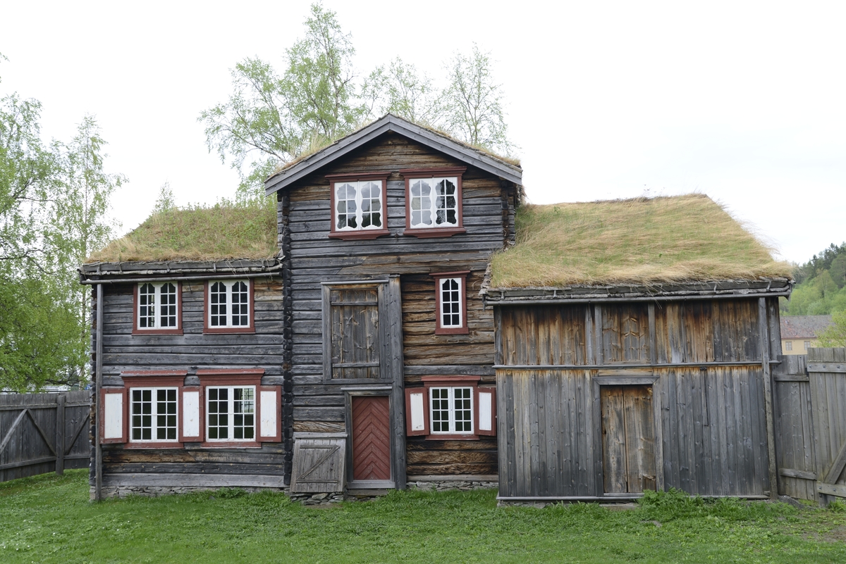 Bergmannsbolig av tømmer. Kledd med tømmermannspanel på gatefasaden. Taket er tekt med never og torv. Fasadeutstyret mot det offentlige rom holder en veldig høy standard. Bygningen er satt sammen av flere (to) eldre bolighus. Den tverrstilte midtarken er sekundært plassert oppå de sammenstilte bygningskroppene. Boligen fra Aspåsgården er sannsynligvis påbegynt  tidlig på 1700-tallet. Senere utvidet og mye forandret. Blant annet er det påbygd to omfar i hele 2. etg. og det er også satt inn større vinduskarmer. Trolig er dette skjedd i siste del av 1800-tallet. Det er gjenbrukt bygningselementer fra et sosialt høyere sjikt. Bygningen har to rom med fyllingspanelte vegger. - Et  rom i 2. etg. og et i midtarken. Disse to rommene har fått sine nytilvirkede veggpaneler etter at de har fått nåværende romhøyde og etter at det er satt inn større vinduskarmer. Bygningen er endret helt inn mot 1900-tallet.  Pløyd panel, brukt i bislag mot bakgården, representerer et siste trinn i Rørosbebyggelsens utviklingshistorie. Sto på Flanderborg, Røros. Gjenreist på Sverresborg 1917. I forbindelse med oppføringa på museet har bygningen vært gjenstand for omfattende tilbakeføringsforsøk, med blant annet ens vindusrammer for hver etasje. Ikke noe av det gamle panelet på gatefasaden er gjenbrukt. Nytt panel har også fått en annen utbredelse og underdeling enn tidligere. På Røros var bl. a. også grundmuren dekt av panel. Alt tømmermannspanel er nytt fra 1917. Dagens utseende er eksteriørmessig utvilsomt museumsskapt. Endringene, som er gjennomført på museet, har bidratt til klart å svekke et veldig godt eksempel på folkelig, lokal byggeskikk. 