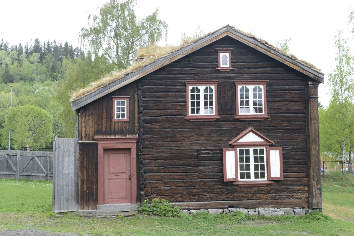 Bergmannsbolig av tømmer. Kledd med tømmermannspanel på gatefasaden. Taket er tekt med never og torv. Fasadeutstyret mot det offentlige rom holder en veldig høy standard. Bygningen er satt sammen av flere (to) eldre bolighus. Den tverrstilte midtarken er sekundært plassert oppå de sammenstilte bygningskroppene. Boligen fra Aspåsgården er sannsynligvis påbegynt  tidlig på 1700-tallet. Senere utvidet og mye forandret. Blant annet er det påbygd to omfar i hele 2. etg. og det er også satt inn større vinduskarmer. Trolig er dette skjedd i siste del av 1800-tallet. Det er gjenbrukt bygningselementer fra et sosialt høyere sjikt. Bygningen har to rom med fyllingspanelte vegger. - Et  rom i 2. etg. og et i midtarken. Disse to rommene har fått sine nytilvirkede veggpaneler etter at de har fått nåværende romhøyde og etter at det er satt inn større vinduskarmer. Bygningen er endret helt inn mot 1900-tallet.  Pløyd panel, brukt i bislag mot bakgården, representerer et siste trinn i Rørosbebyggelsens utviklingshistorie. Sto på Flanderborg, Røros. Gjenreist på Sverresborg 1917. I forbindelse med oppføringa på museet har bygningen vært gjenstand for omfattende tilbakeføringsforsøk, med blant annet ens vindusrammer for hver etasje. Ikke noe av det gamle panelet på gatefasaden er gjenbrukt. Nytt panel har også fått en annen utbredelse og underdeling enn tidligere. På Røros var bl. a. også grundmuren dekt av panel. Alt tømmermannspanel er nytt fra 1917. Dagens utseende er eksteriørmessig utvilsomt museumsskapt. Endringene, som er gjennomført på museet, har bidratt til klart å svekke et veldig godt eksempel på folkelig, lokal byggeskikk. 