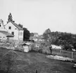 Suddig men unik vy från Linköping. Fotografen stod ungefärligen på platsen för dagens västra landfäste av Drottningbron. Närmast till vänster ses bebyggelsen i det forna Tannefors kvarter nr. 27 som till delar tillhörde Jon Asklunds tobaksfabrik. I fonden skymtar Stångebro som den såg före Kinda kanals tillkomst i början 1870-talet. Fototiden uppskattad till omkring 1865.