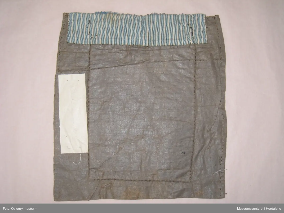 Brodert med ullgarn i plattsaum. Alt er handlaga. Hovudmotiv er små åttebladroser i border. Oppe er det påsydd eit blått silkeband med eit breitt gullband (i forgylt sølvtråd) utanpå silkebandet. Alt er montert på eit tynt, vokset bomullslerret. Oppe på baksida er det eit ekstra bomullstoff (blåstripet). Bokstavane BODM er broderte inn nede på bringeduken i kross-sting.