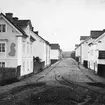 Suddig men unik vy från Linköping. Drottninggatan sedd västerut från Magasintorget. Avsaknaden av senare, känd förändring av miljön daterar bilden till före 1869. Fototiden uppskattad till omkring 1865.