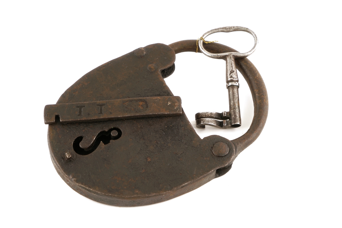 Hengelås av jern, oval med svingbart lokk over nøkkelhull.
Nøkkel av jern med skjegg formet somkroker. Gjennombrudt.