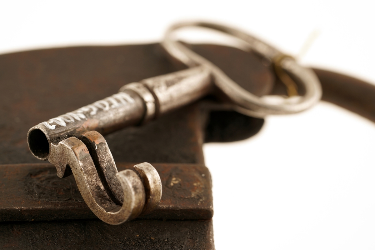 Hengelås av jern, oval med svingbart lokk over nøkkelhull.
Nøkkel av jern med skjegg formet somkroker. Gjennombrudt.