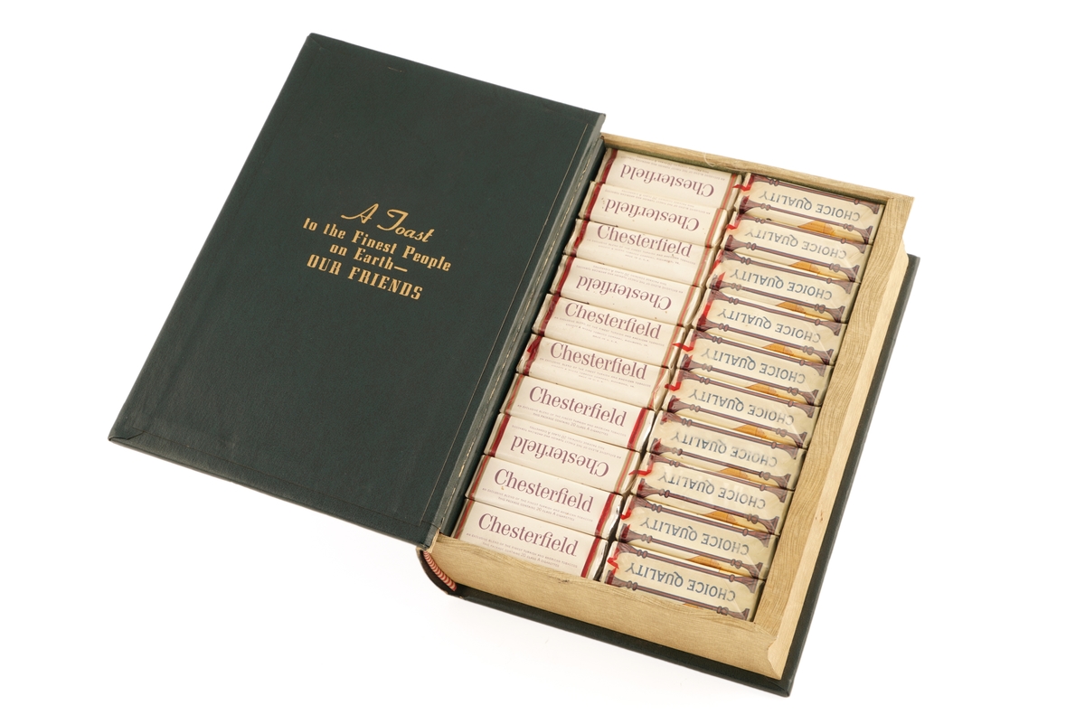 Bok i mørk grønt skinn. Det som skulle være boksider, er treverk. Dette er uthult for å romme sigaretter.