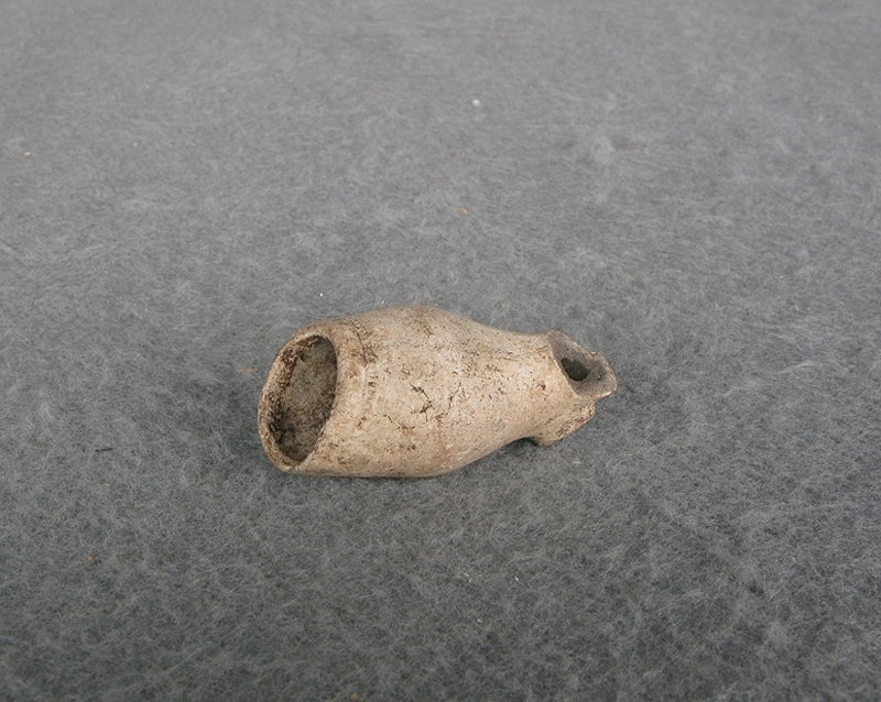 Arkeologiskt föremål. Del av en kritpipa, piphuvud av vit-bränd piplera. Vitt.