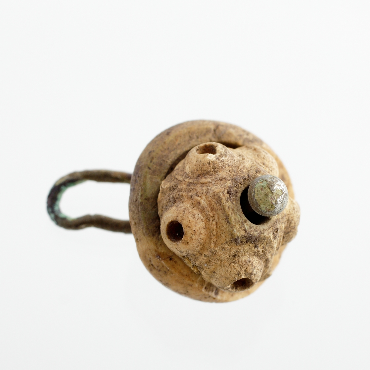 Knapp som utgörs av en svarvad, halvklotformig knopp. Denna är ornerad med fem små, utstående "ögon". Knoppen vilar på en platt, svarvad del med urtag för den övre knoppen. De båda delarna är sammanhållna av en 1 mm tjock tråd av förtent koppar, som med ett klotrunt huvud bildar spetsen på knoppen. Mycket nött.