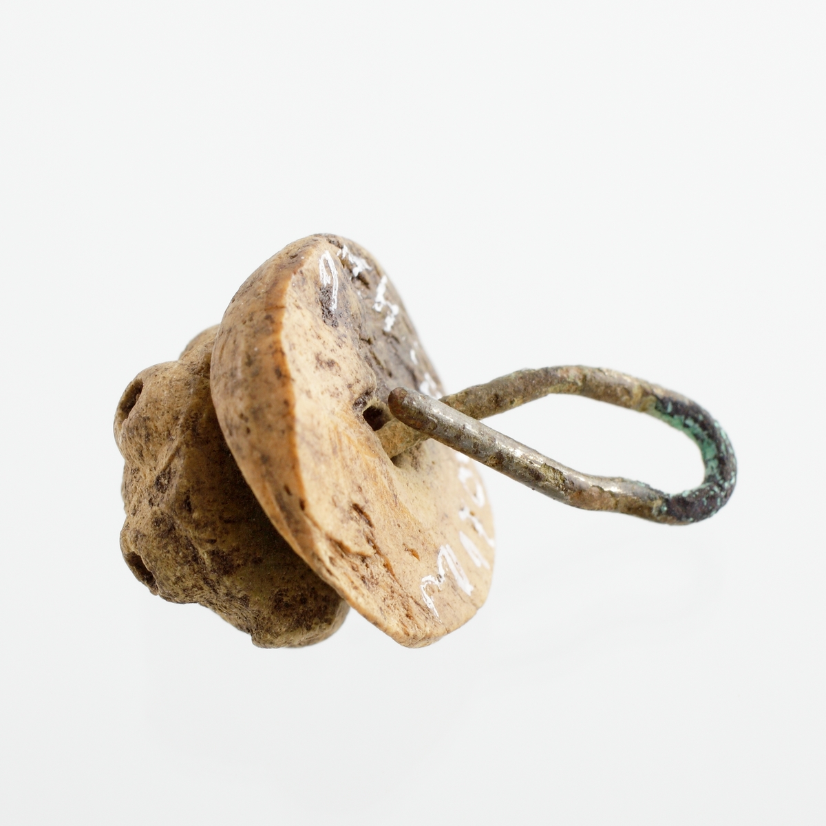 Knapp som utgörs av en svarvad, halvklotformig knopp. Denna är ornerad med fem små, utstående "ögon". Knoppen vilar på en platt, svarvad del med urtag för den övre knoppen. De båda delarna är sammanhållna av en 1 mm tjock tråd av förtent koppar, som med ett klotrunt huvud bildar spetsen på knoppen. Mycket nött.