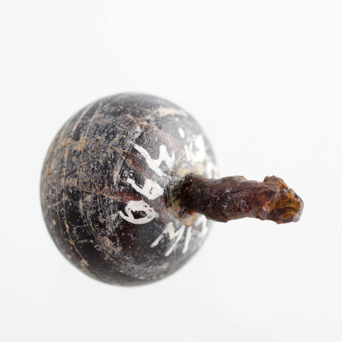 Klotformad knapp av svart, opak glasfluss med vit marmorering. Matt glasyta. En stump av järnöglan sitter kvar. Tidigare tolkad som en recent nål. Se Referenser/Digitala objekt för liknande knapp i 1500-1600-talskontext.