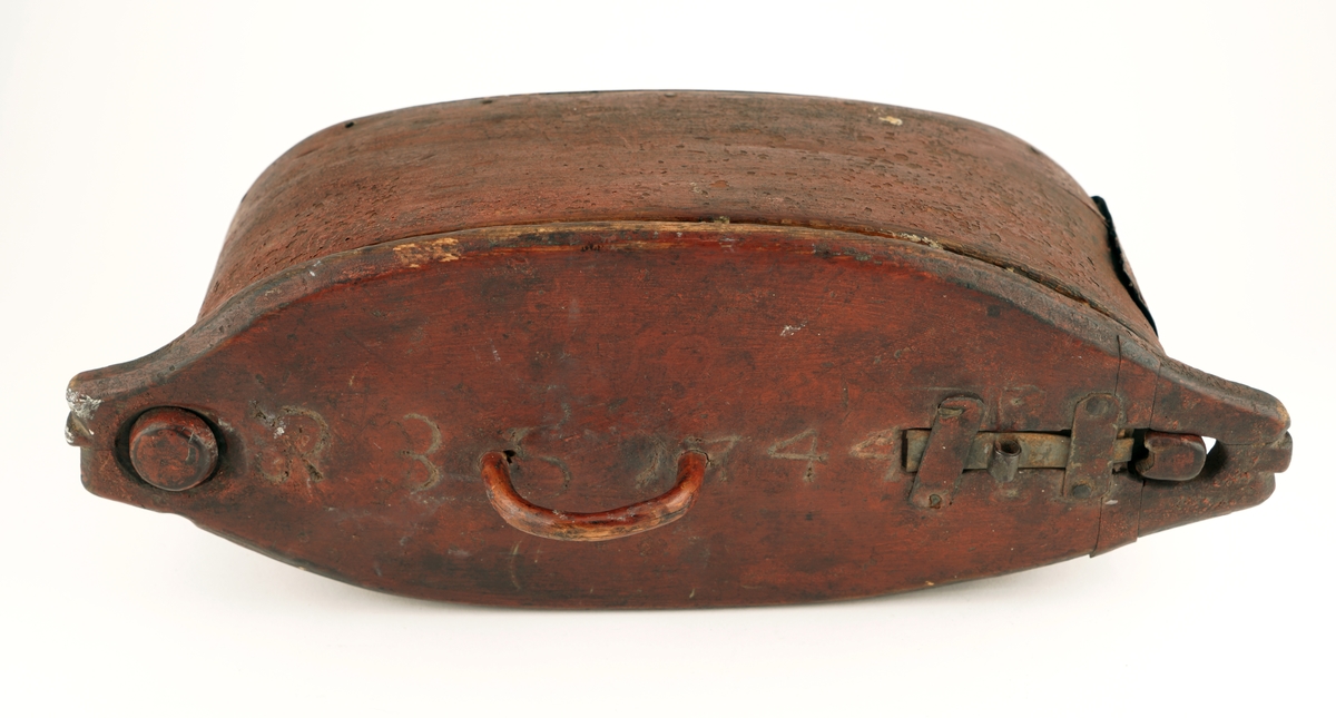 Nistelaup av rødmalt tre. Oval med svingbart lokk, festet i den ene enden med en trenagle. Hank og lås på lokket.