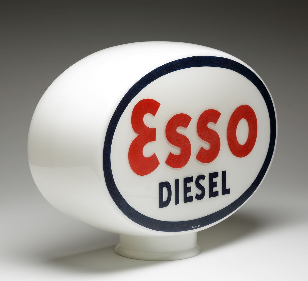 Reklamlampa/skyltglas för Esso.
Oval kupa av opakt mjölkglas. På de platta sidorna försedd med en målad, svart ring, därinom ett rött "Esso" och i svart "Diesel".
Glaset satt överst på bensinpumpen.
Bolaget "STANDARD" bytte namn till "ESSO" den 15 maj 1939 ("Mackboken" sid 17, av Kjell Eliasson och Ewa Forsberg). Smålands museum fick glaset av Böhlmarks 20 nov 1938: Troligen är det bland de första Esso-skyltarna som tillverkades i Sverige.
Blåst fast i form. Målad text enligt ovan.

Inskrivet i huvudkatalogen 1939.