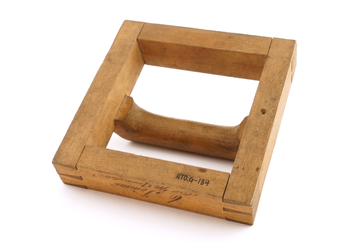 Ramme av tre med håndtak.Til utklipping av over - eller undervektige ull - eller bomulls-
varer.
Utydelig skrift rundt rammen.