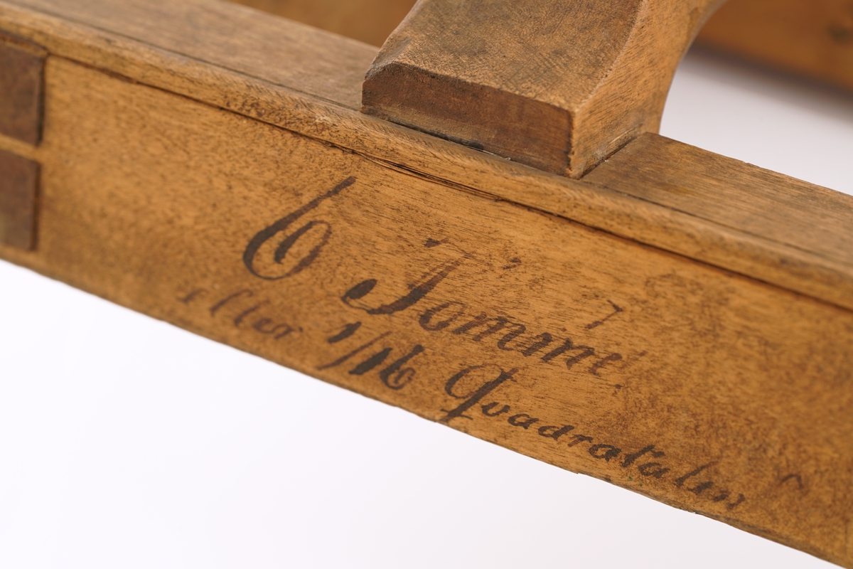 Ramme av tre med håndtak.Til utklipping av over - eller undervektige ull - eller bomulls-
varer.
Utydelig skrift rundt rammen.