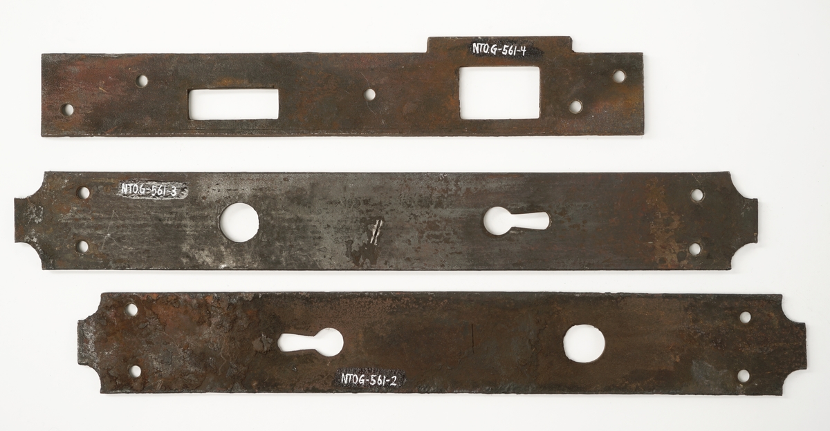 Dørlås for innmontering i dør av jern. Det medfølger tre monteringsbraketter, som selve låsen har vært montert på. Låskassen er rektangulær, med avrundede hjørner på den ene siden, og et større, flatt jern på den motsatte siden.Nøkkel følger med