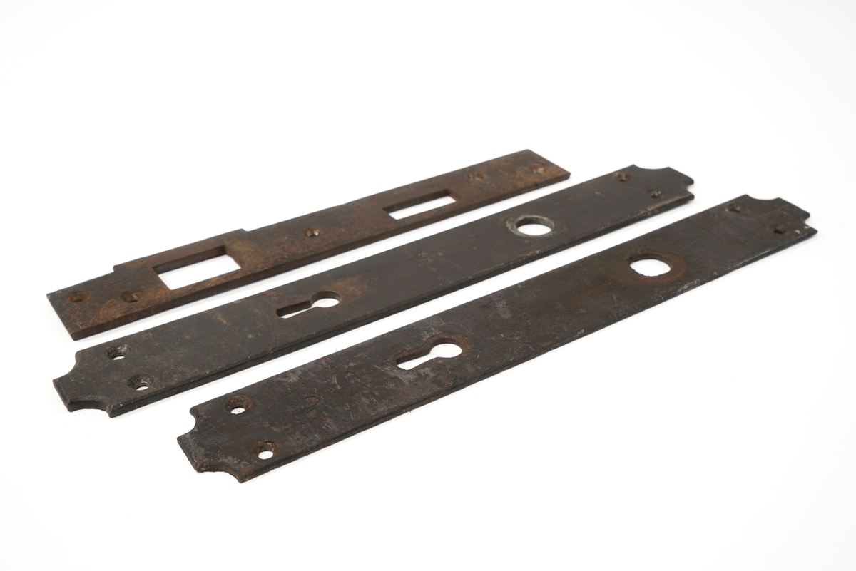 Dørlås for innmontering i dør av jern. Det medfølger tre monteringsbraketter, som selve låsen har vært montert på. Låskassen er rektangulær, med avrundede hjørner på den ene siden, og et større, flatt jern på den motsatte siden.Nøkkel følger med