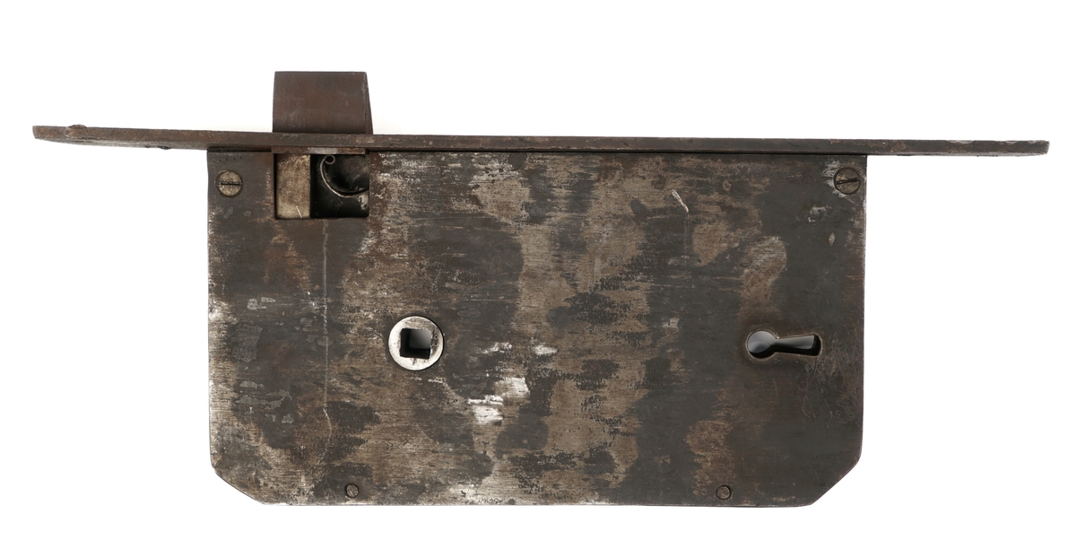Dørlås for innmontering i dør av jern. Det medfølger tre monteringsbraketter, som selve låsen har vært montert på. Låskassen er rektangulær, med avrundede hjørner på den ene siden, og et større, flatt jern på den motsatte siden.Nøkkel følger med