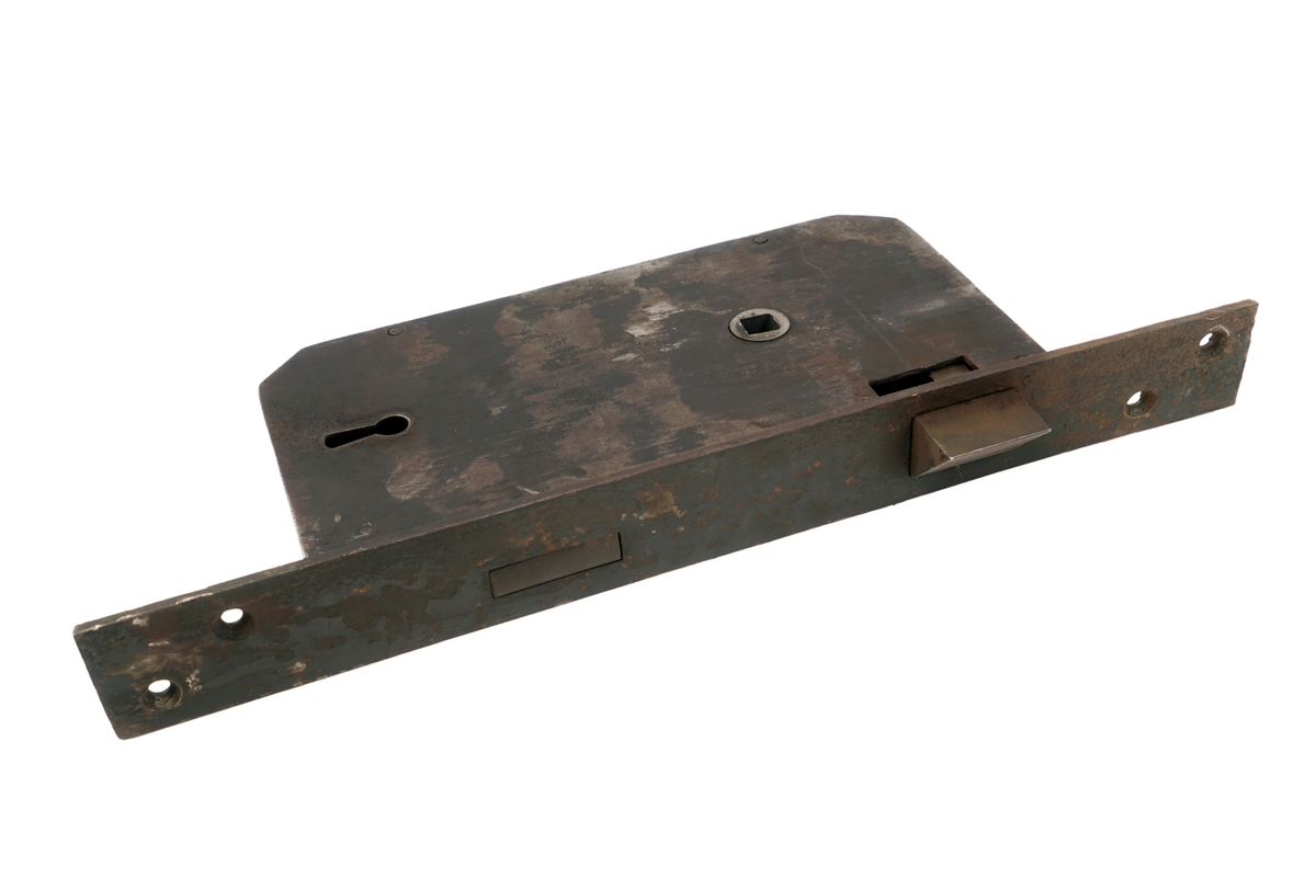Dørlås for innmontering i dør av jern. Det medfølger tre monteringsbraketter, som selve låsen har vært montert på. Låskassen er rektangulær, med avrundede hjørner på den ene siden, og et større, flatt jern på den motsatte siden.Nøkkel følger med