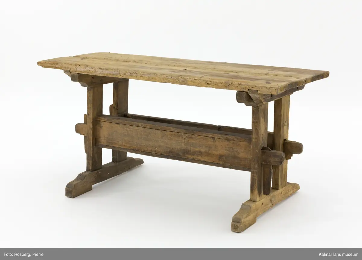KLM 11169. Bord, långbord. Av furu. Avlångt bord med två ben på vardera kortsida samt lös bordsskiva med rektangulär form. Undertill en avlång låda som håller samman benen. Omålat. Väl använt.